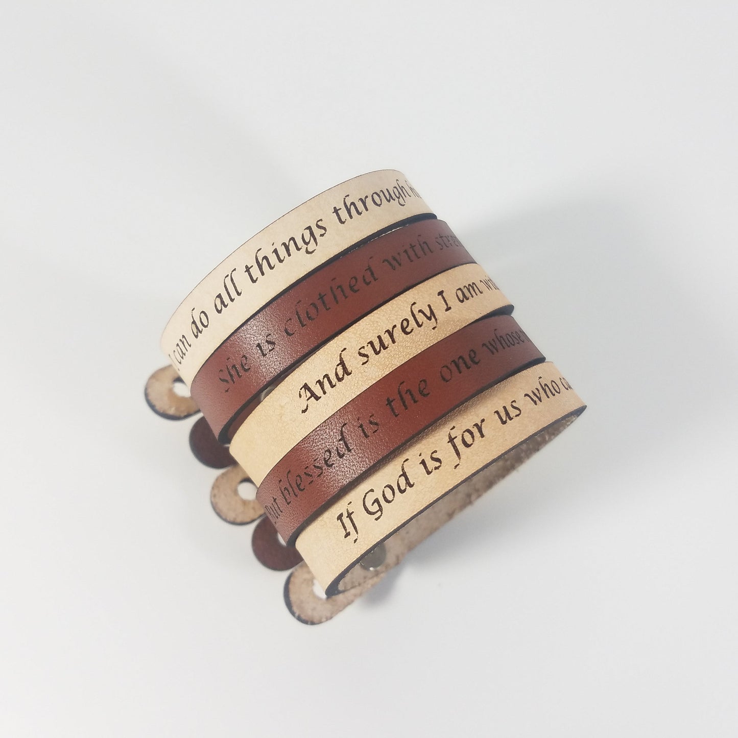 Set of leather bracelets with engraved text on a light gray background