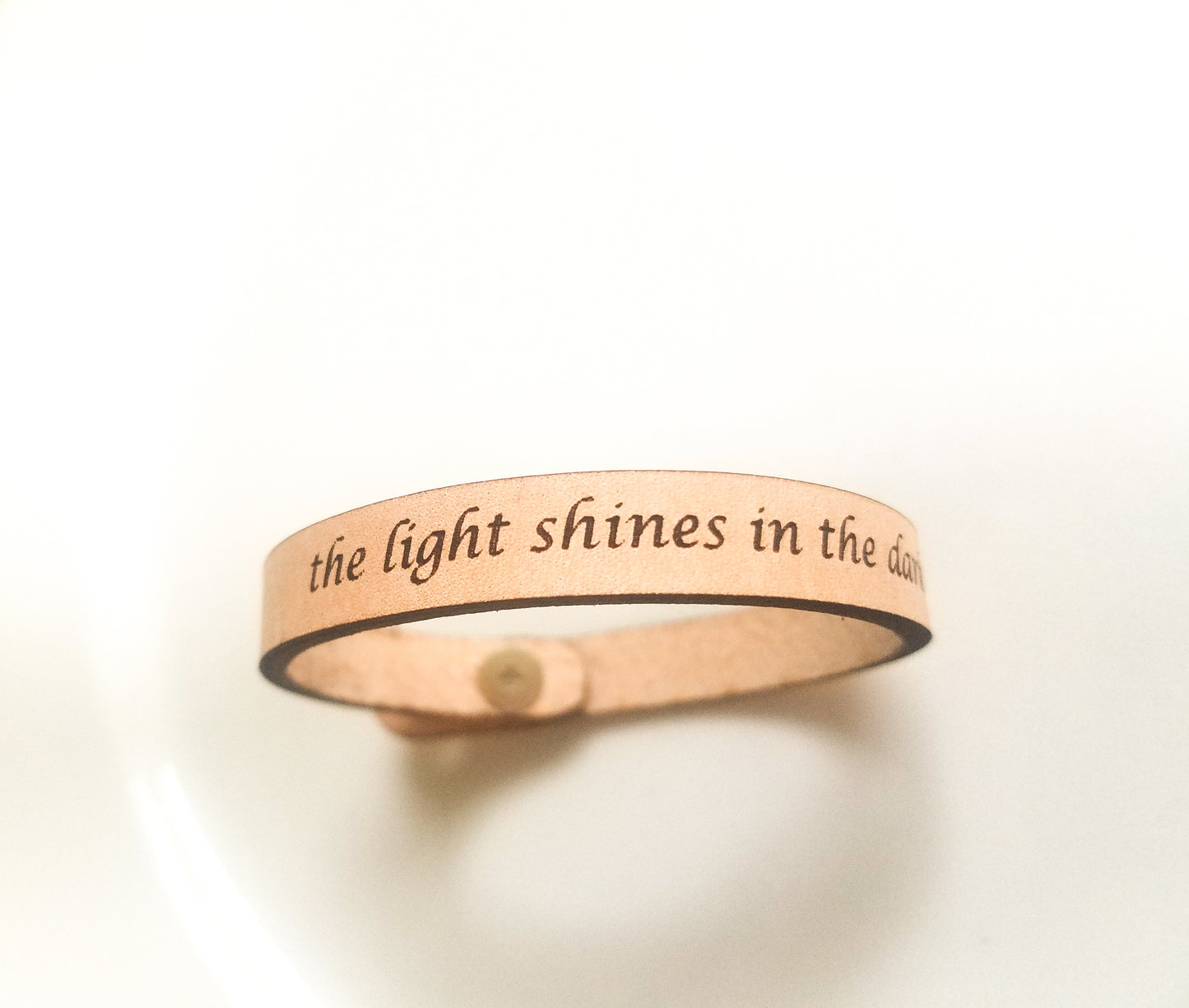 Rose gold bracelet with engraved text on a white background