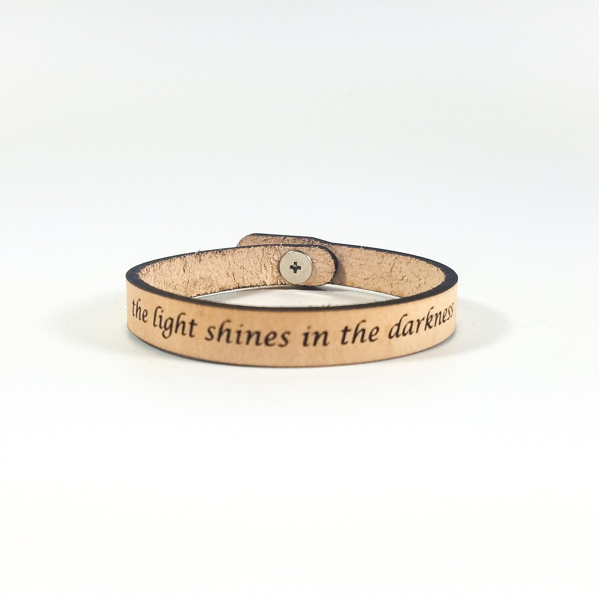 Leather bracelet with engraved text on a white background