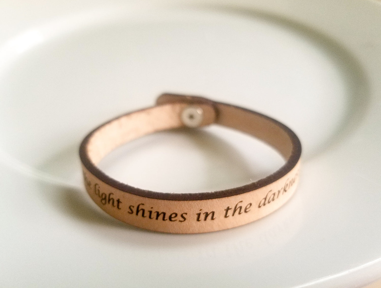 Leather bracelet with engraved text on a white background